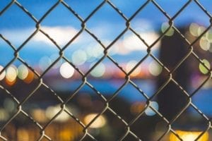 a chainlink fence and city lights